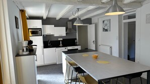 Een moderne keuken met witte kasten, een centraal eiland en hangende lampen.
