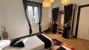 Een slaapkamer met een bed, een kledingkast, een klein tafeltje en een hanglamp.