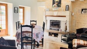 Un amplio espacio de sala de estar con chimenea, mesa de comedor y asientos cómodos.