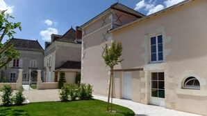 Un immeuble résidentiel avec une allée pavée, une petite pelouse et un arbre.