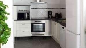 Une cuisine de taille réduite avec des meubles blancs, un four à micro-ondes, une cuisinière et un réfrigérateur.