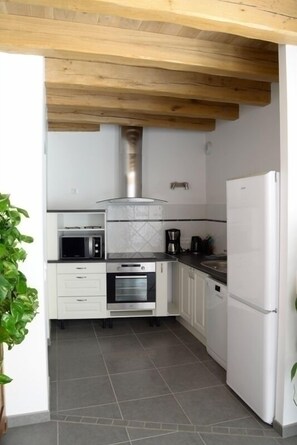 Une cuisine de taille réduite avec des meubles blancs, un four à micro-ondes, une cuisinière et un réfrigérateur.