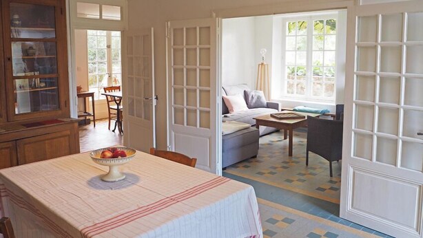 Amplia sala de estar con comedor, sofá, mesa de centro y estantería.