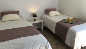 Quarto de hotel com duas camas, uma mesa de cabeceira com abajur e um tabuleiro com suco.