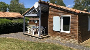 Uma cabana de madeira com alpendre coberto, antena parabólica e janela com persianas.