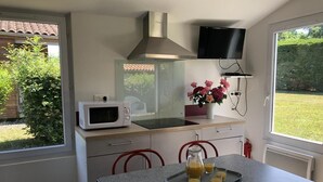 Uma cozinha equipada com micro-ondas, pia, fogão, televisão e uma mesa com uma bandeja de sumo de laranja.