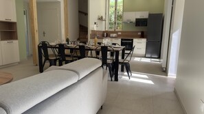 A modern kitchen with a dining area, a bench, and a view of the outside. - Au clair de la Rhune (MARCAY)