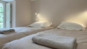 Ett sovrum med två sängar, ett fönster och en taklampa.
