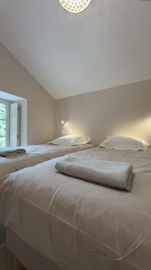 Een slaapkamer met twee bedden, een raam en een plafondlamp.