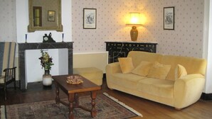 Uma sala de estar com sofá, mesa, lareira e espelho.