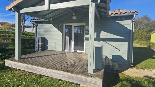 A small, single-story building with a covered porch, a sliding glass door, and a small outdoor seating area. - Spotted Woodpecker - SAULGE (SAULGE)