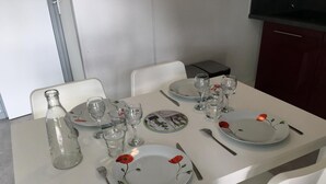 A dining table set with plates, cutlery, and glasses, with a bottle and a small container on the left. - Spotted Woodpecker - SAULGE (SAULGE)