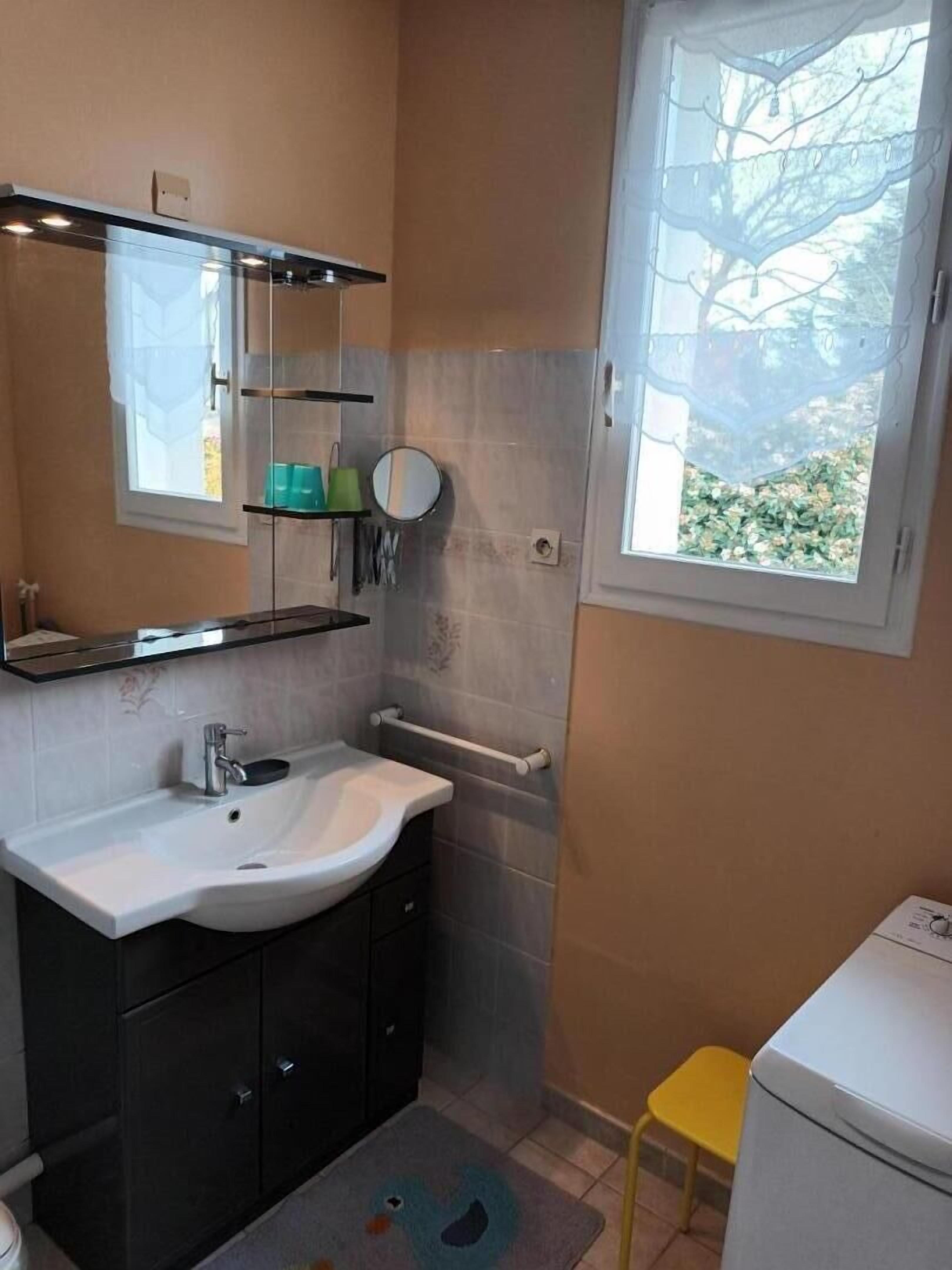 Un bagno con lavandino, specchio, mensole e una finestra.