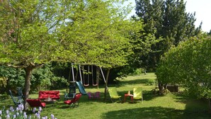 A garden with a swing set, chairs, and a table. - GITE DE M'et Mme AUGUSTE (VOUNEUIL-SUR-VIENNE)
