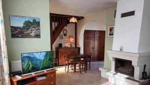 A living room with a TV, wooden furniture, a fireplace, and a dining area. - GITE DE M'et Mme AUGUSTE (VOUNEUIL-SUR-VIENNE)
