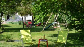 A park with green chairs, a small table, and a swing set. - GITE DE M'et Mme AUGUSTE (VOUNEUIL-SUR-VIENNE)