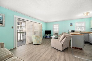 A compact living space with a kitchenette, a sofa, a dining table, and a TV. - Three Bedroom Oceanside Condo Steps from the Beach (Ocean City)
