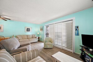 Un salon avec un canapé, un fauteuil et un téléviseur.