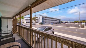 Un espace extérieur abrité offrant une vue sur une rue, un immeuble et des voitures garées.