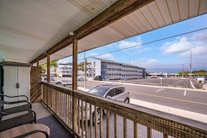 A covered outdoor area with a view of a street, a building, and parked cars. - Three Bedroom Oceanside Condo Steps from the Beach (Ocean City)