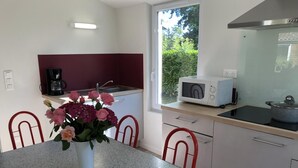 A kitchen with a dining table, chairs, a microwave, a coffee maker, and a window with a view of greenery. - Chalet N° 1 - SAINT SECONDIN (SAINT SECONDIN)