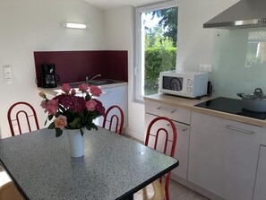 A kitchen with a dining table, chairs, a microwave, a coffee maker, and a window with a view of greenery. - Chalet N° 1 - SAINT SECONDIN (SAINT SECONDIN)