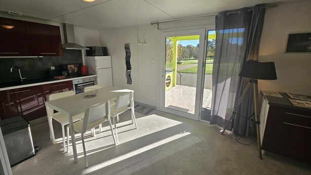 A compact kitchen with a dining area, a refrigerator, a microwave, and a small table with chairs.