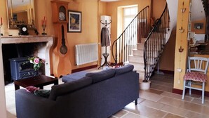Uma sala de estar com sofá, lareira, relógio e escada.