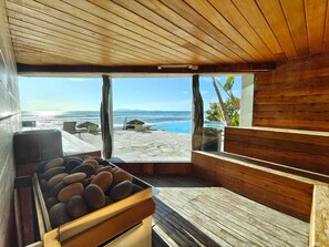 A wooden deck with a stone basin, a view of the ocean, and a clear sky. - Oceanfront 3BR Baja - Pool, Sauna, Gym & Beach (Playas de Rosarito)