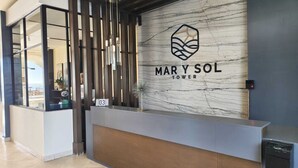 A reception desk with a marble wall, a logo, and a digital clock.