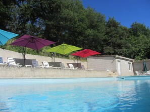 Uma piscina com espreguiçadeiras e guarda-sóis.
