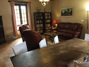 A living room with a brown leather sofa, a wooden coffee table, a bookshelf, and a lamp. - Le Vallon - MONDION - Gîte (MONDION)