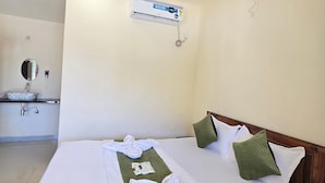 Ein Hotelzimmer mit Bett, Nachttisch, Spiegel, Waschbecken und Klimaanlage.