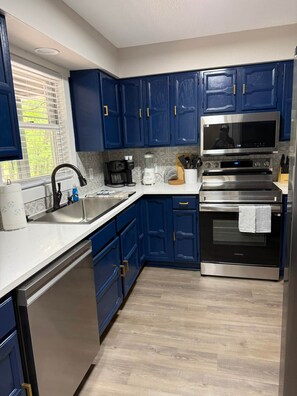A modern kitchen with blue cabinets, stainless steel appliances, and a dishwasher. - Hot Springs Village Renovated Townhome Retreat (Hot Springs Village)