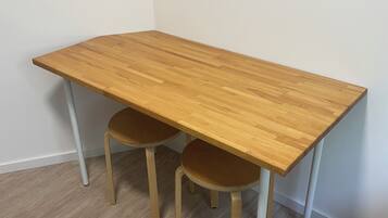 Ein rechteckiger Holztisch mit zwei Stühlen, eine weiße Wand und ein Holzboden.