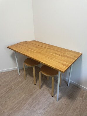Ein rechteckiger Holztisch mit zwei Stühlen, eine weiße Wand und ein Holzboden.
