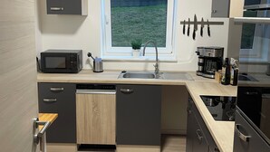 Una cocina moderna con microondas integrado, un fregadero y una ventana con vistas a una zona verde.