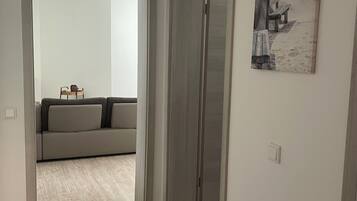 Ein Flur mit Holzboden, einem grauen Sofa und einem Gemälde an der Wand.