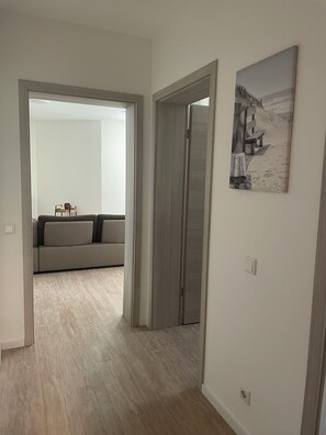 Ein Flur mit Holzboden, einem grauen Sofa und einem Gemälde an der Wand.
