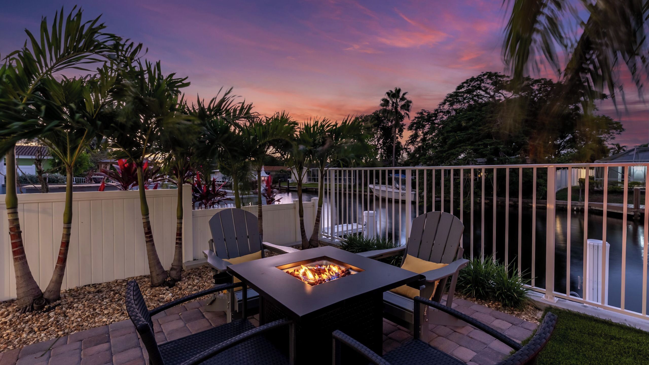 Eine Terrassenanlage im Freien mit Feuerstelle, Sitzgelegenheiten und Blick auf ein Gewässer.