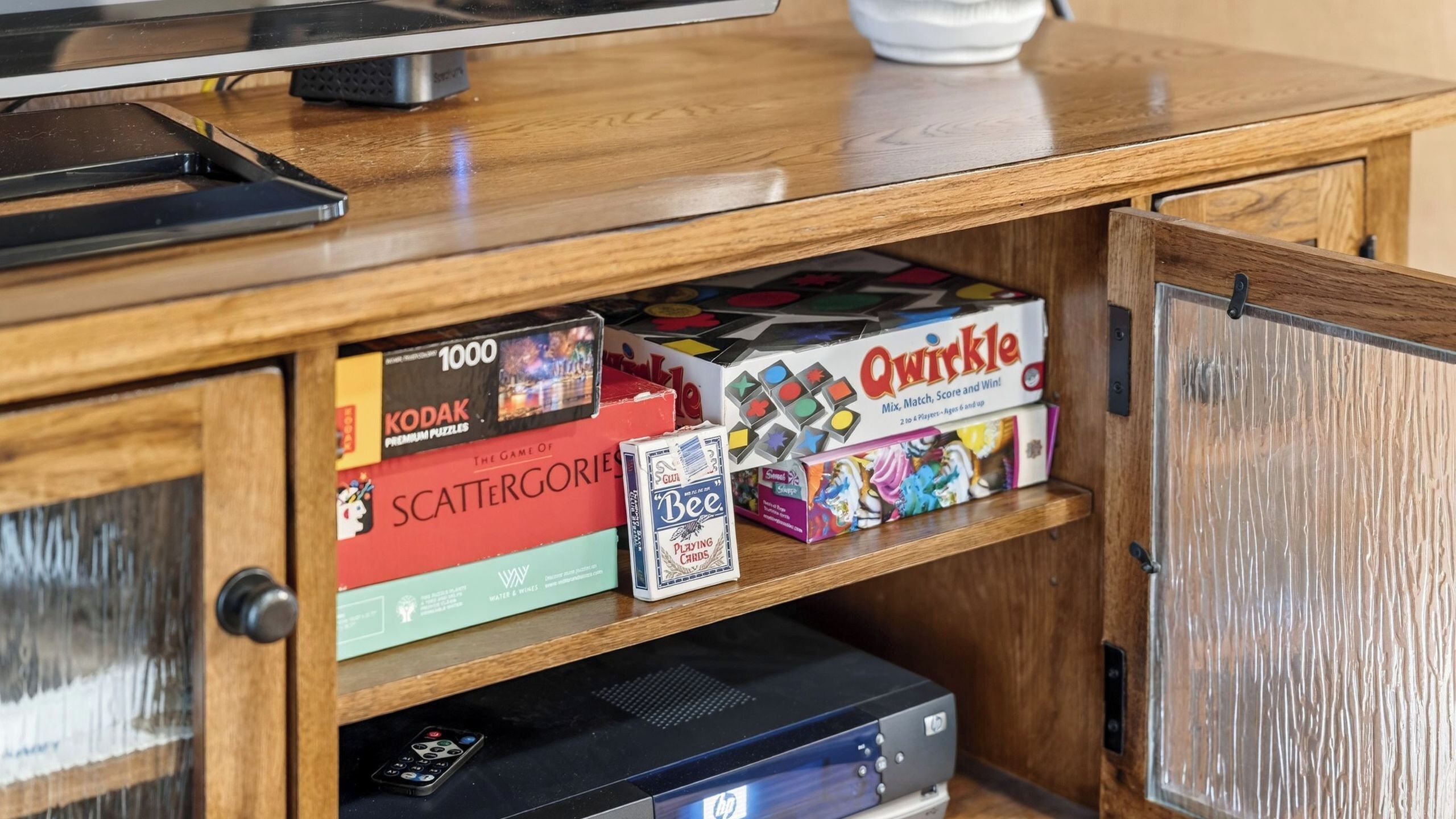 Un mueble de madera con un televisor encima, que contiene varios juegos de mesa y un reproductor de DVD.