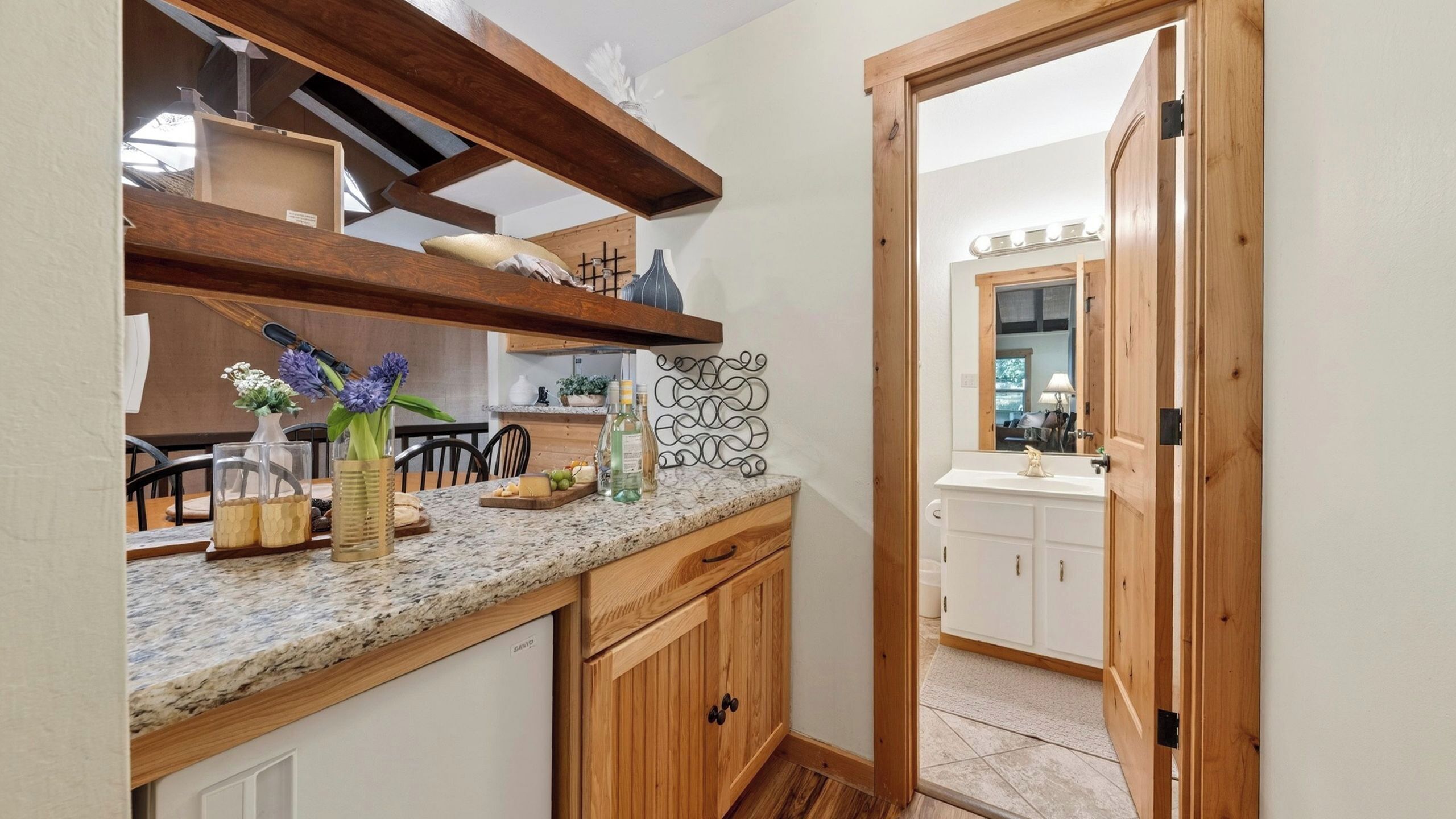 Una cocina con armarios de madera, encimera de granito y vista hacia otra habitación.