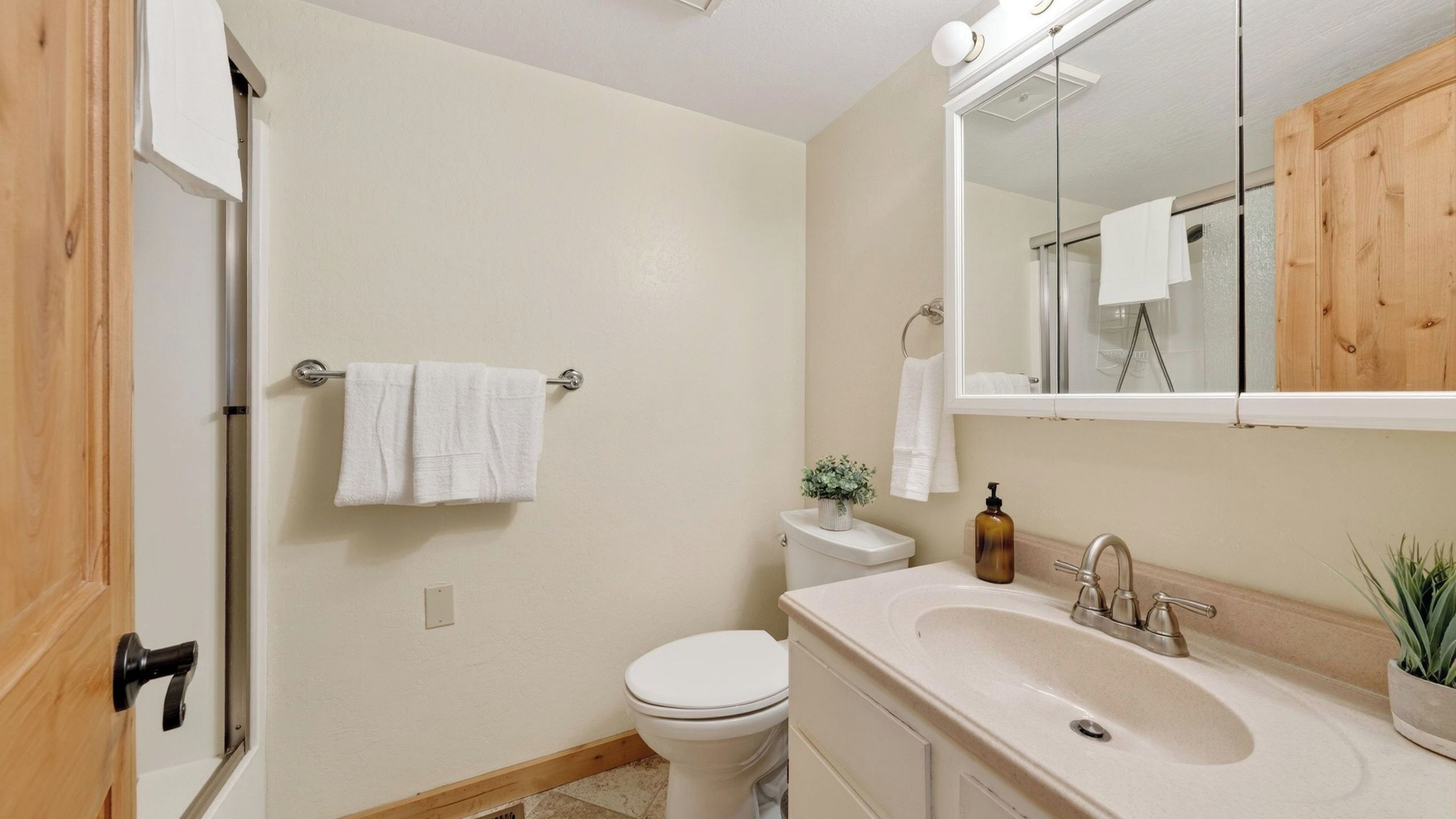 Baño con inodoro, lavabo, espejo y barra para toallas.