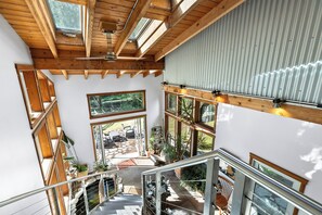 Un intérieur à plusieurs niveaux, avec des poutres en bois, de grandes fenêtres et un escalier.