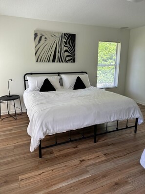 A bedroom with a bed, a nightstand, a zebra print artwork, and a window with blinds. - Private 3/2 5 min from WEC Ocala (Ocala)