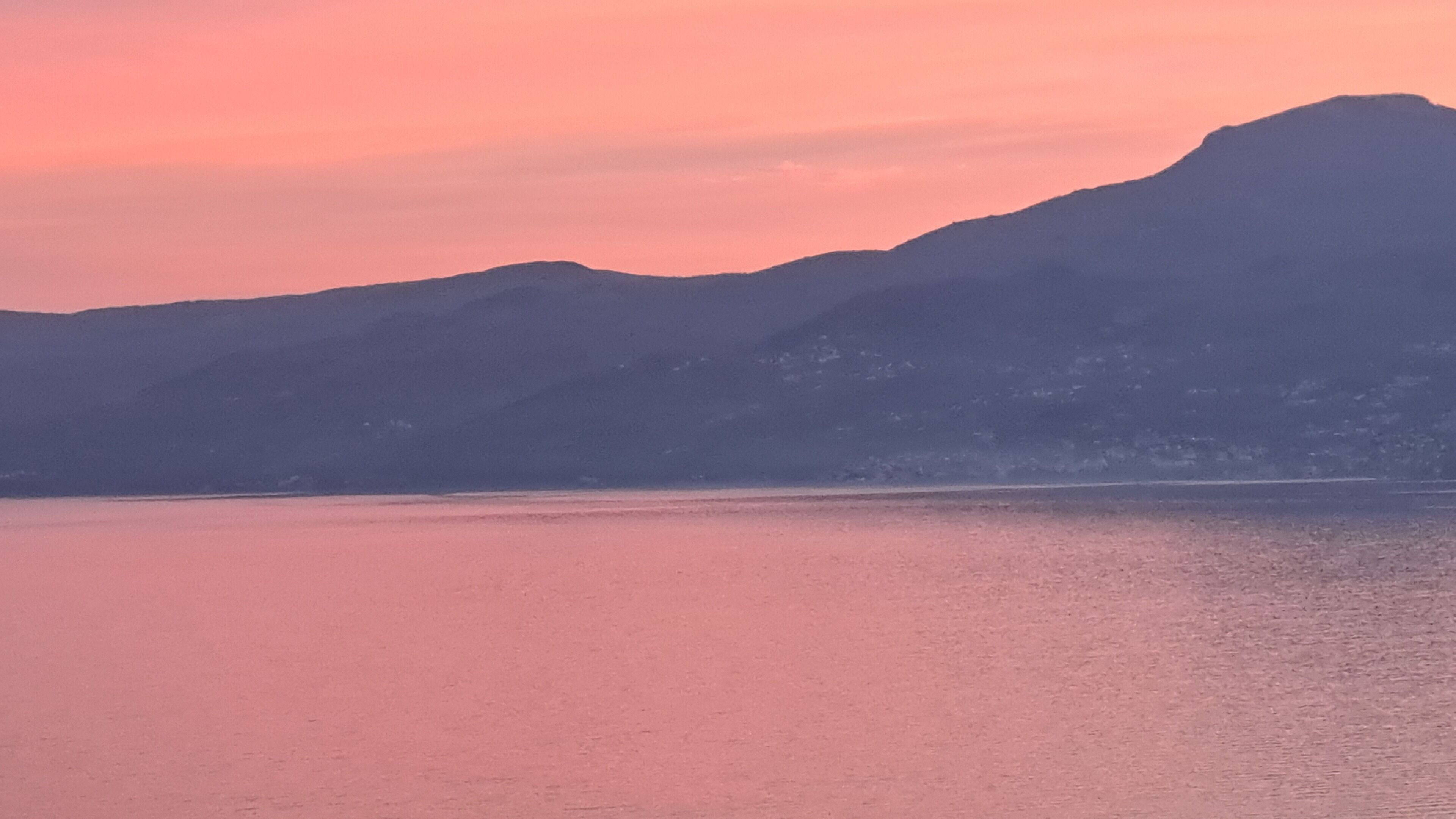 Une chaîne de montagnes avec un plan d’eau au premier plan.