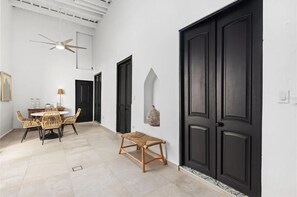 Ein Zimmer mit Esstisch, Stühlen, Deckenventilator und einer großen schwarzen Tür.
