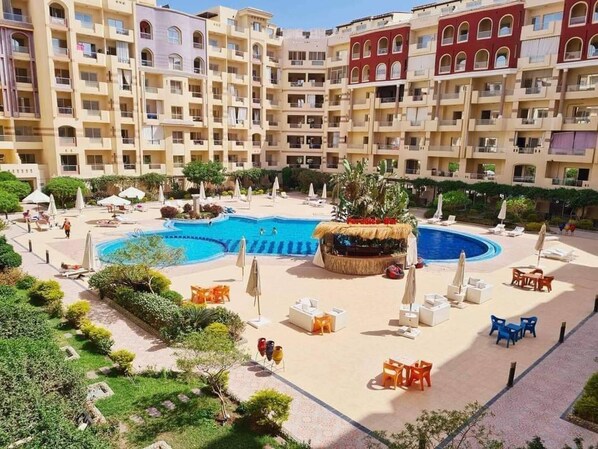 A hotel with a central swimming pool, outdoor seating, and a lush garden. - Room-florence Khamsin Hurghada K203 (Hurghada)
