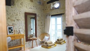 Une chambre à coucher avec un lit, une commode en bois, une chaise, un miroir et une fenêtre.