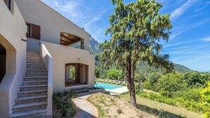 Una casa moderna con piscina, una scala e vista sulle montagne.